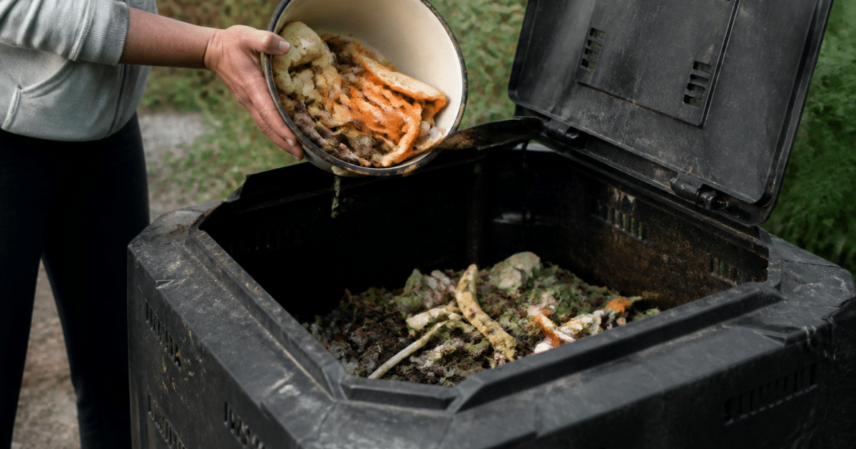 Mains versant dechets organiques dans bac compost ouvert
