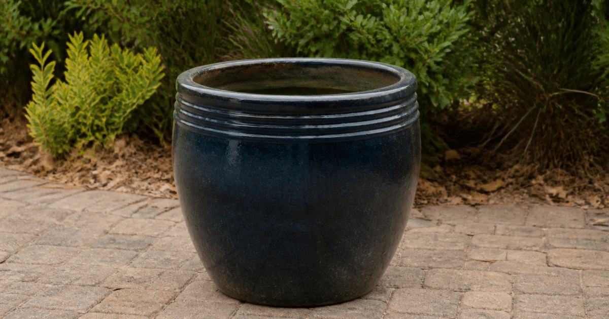 Large ceramic planter sitting upright on outdoor patio ground