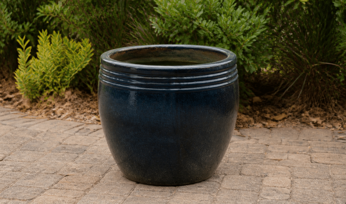 Large ceramic planter sitting upright on outdoor patio ground