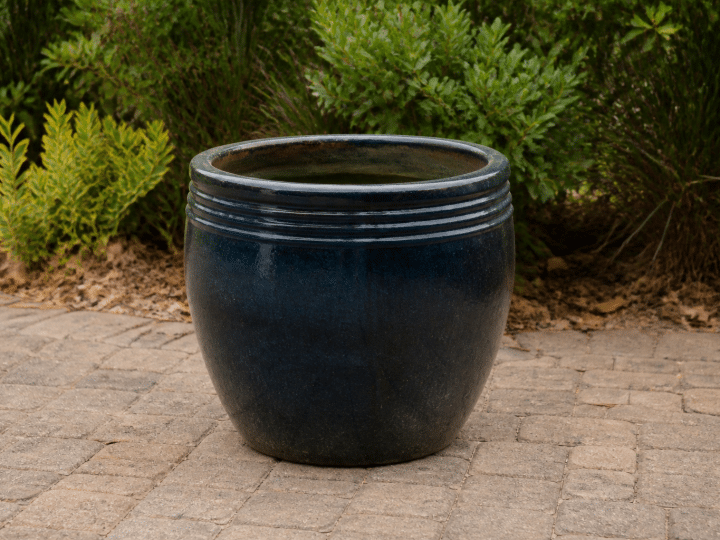Large ceramic planter sitting upright on outdoor patio ground