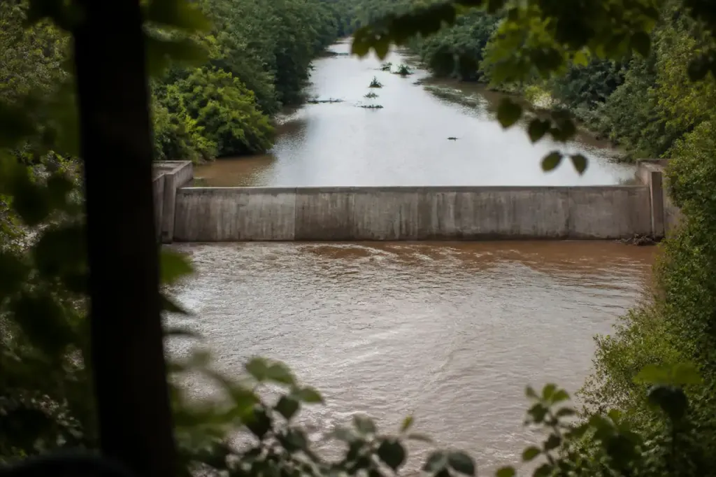 Mur de beton gris barrant une riviere boueuse